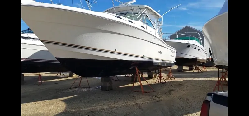 Slide: The Image of 2000 Wellcraft 330 Coastal boat on stands, displayed outdoors under clear blue sky. - 28
