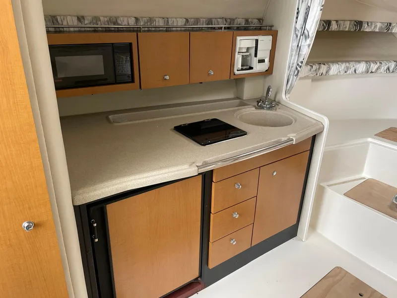 Slide: The Image of Compact kitchen area in a 2000 Wellcraft 330 Coastal boat, featuring cabinets and appliances. - 3