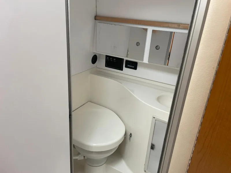 Slide: The Image of 2000 Wellcraft 330 Coastal boat bathroom with toilet, sink, and storage cabinets. - 5