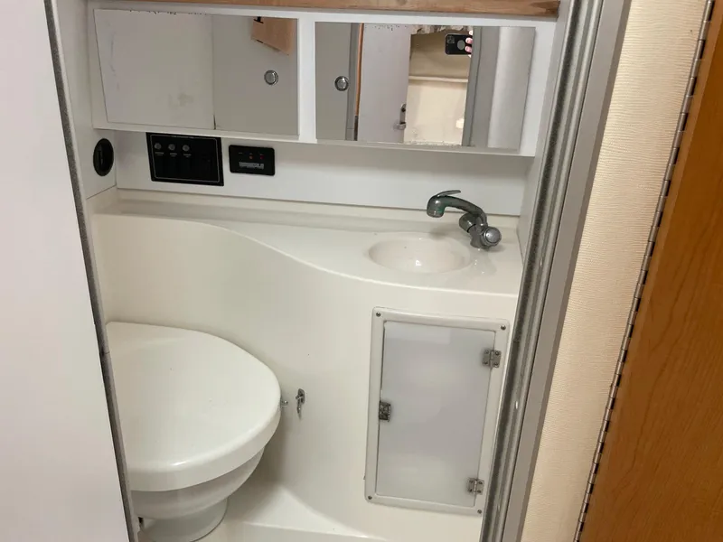 Slide: The Image of Compact bathroom in 2000 Wellcraft 330 Coastal boat with sink, toilet, and mirrored cabinet. - 6