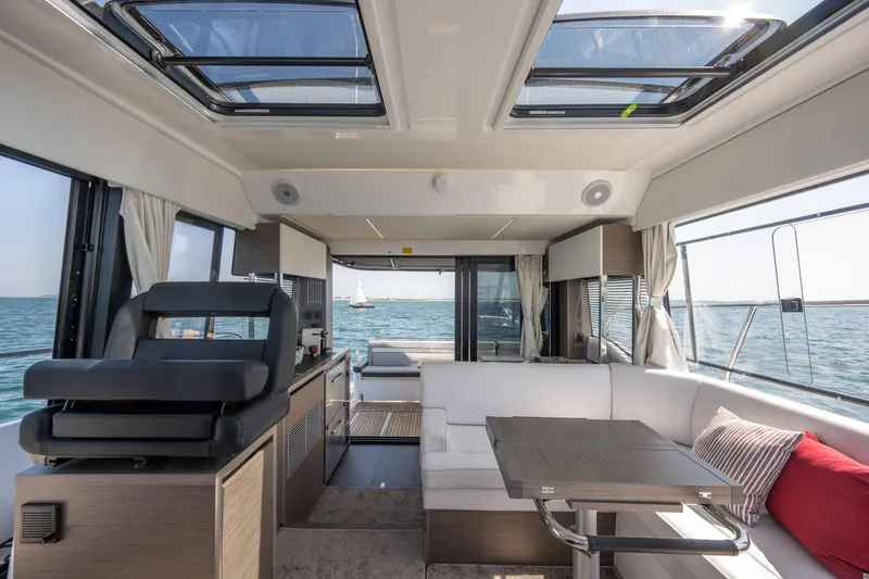 Slide: The Image of Interior of 2025 Jeanneau NC 1295 Coupe yacht with modern seating and ocean view. - 9