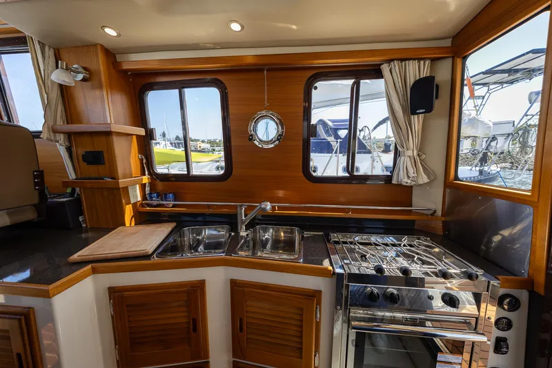 Slide: The Image of 2023 Ranger Tugs R-31 S interior kitchen with stove, sink, and wooden cabinetry. - 14