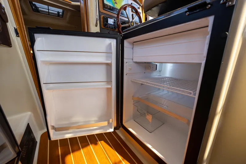 Slide: The Image of 2023 Ranger Tugs R-31 S boat interior with open refrigerator, showcasing storage space. - 21