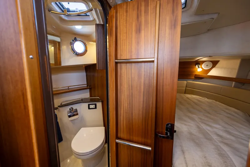 Slide: The Image of 2023 Ranger Tugs R-31 S interior with wooden door, compact bathroom, and cozy sleeping area. - 25
