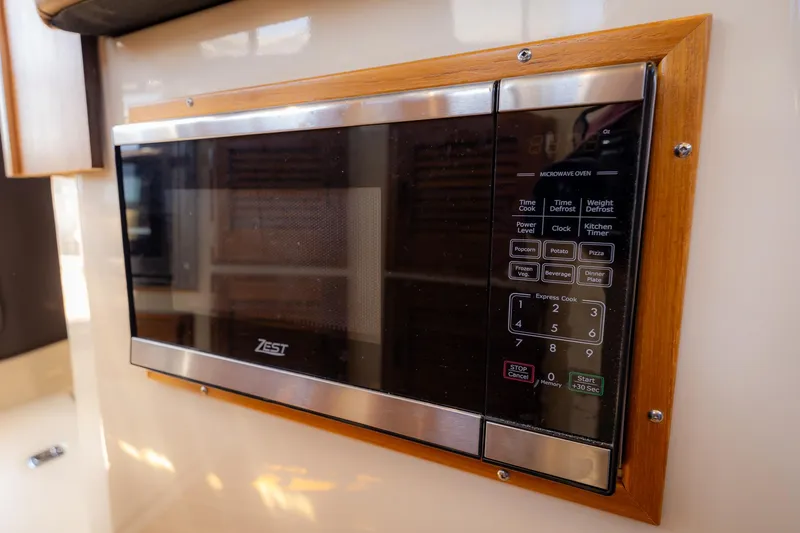 Slide: The Image of Microwave in 2023 Ranger Tugs R-31 S boat kitchen, featuring wood trim and digital controls. - 30