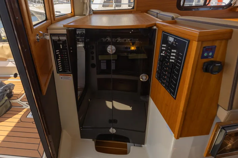 Slide: The Image of 2023 Ranger Tugs R-31 S interior with control panels and wooden cabinetry. - 8