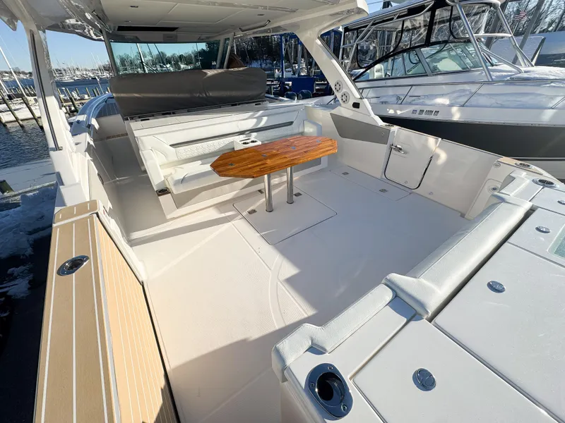 Slide: The Image of 2025 Tiara Yachts 43 LS boat interior with seating and wooden table, docked at marina. - 13