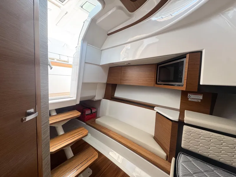 Slide: The Image of 2025 Tiara Yachts 43 LS interior with wooden steps, seating, and built-in microwave. - 18