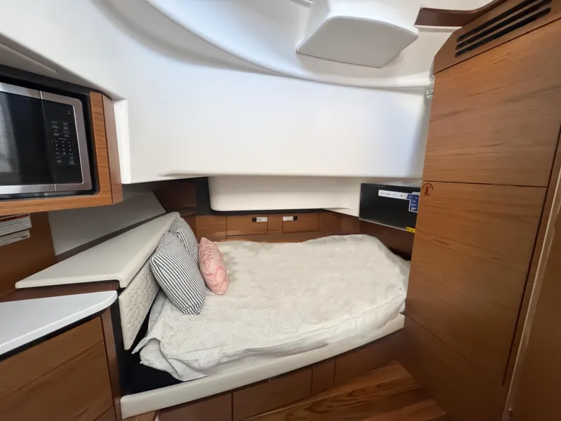 Slide: The Image of 2025 Tiara Yachts 43 LS cabin interior with bed, microwave, and wooden cabinetry. - 21