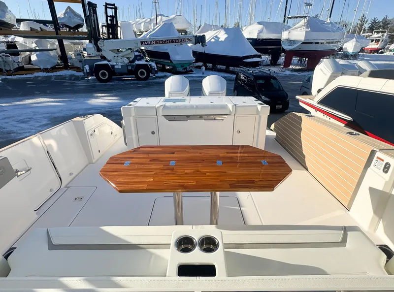 Slide: The Image of 2025 Tiara Yachts 43 LS deck with wooden table, docked among covered boats. - 7