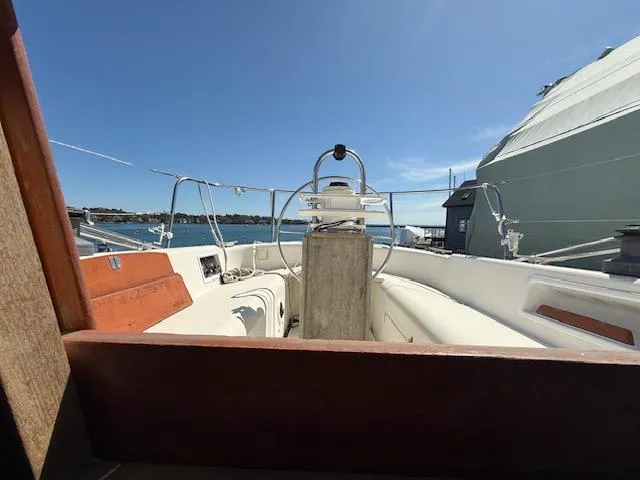 Slide: The Image of 1983 Pearson 303 sailboat cockpit with steering wheel, docked under clear blue sky. - 24