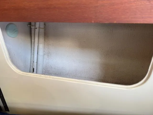 Slide: The Image of Interior view of a 1983 Pearson 303 sailboat showing storage compartment and plumbing. - 25