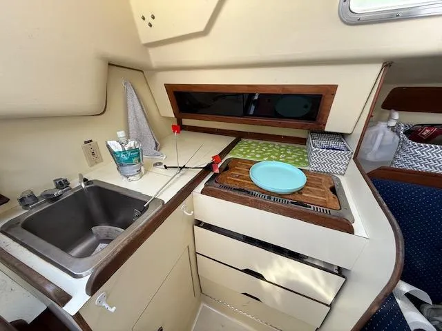 Slide: The Image of Compact kitchen area in a 1983 Pearson 303 sailboat with sink, stove, and storage. - 28