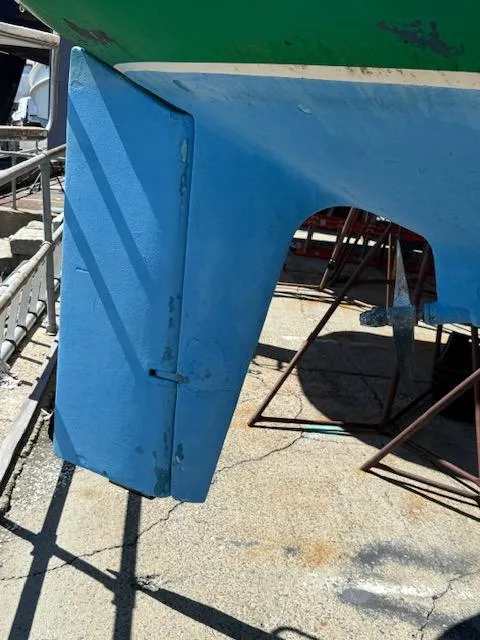 Slide: The Image of 1983 Pearson 303 sailboat rudder in dry dock, showing blue paint and structural details. - 36