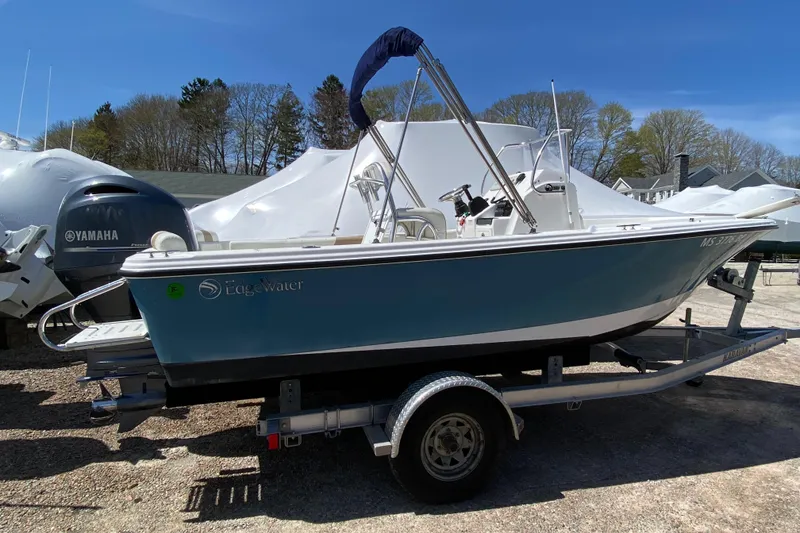 Slide: The Image of 2020 Edgewater 188CC boat on trailer, blue hull, parked outdoors under clear sky. - 19