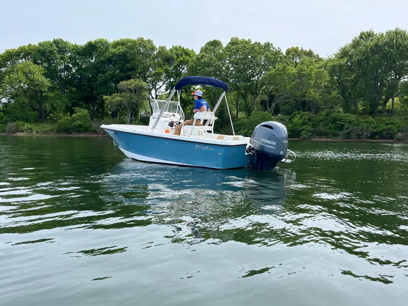 Slide: The Image of 2020 Edgewater 188CC boat cruising on a calm lake with lush green trees in the background. - 9