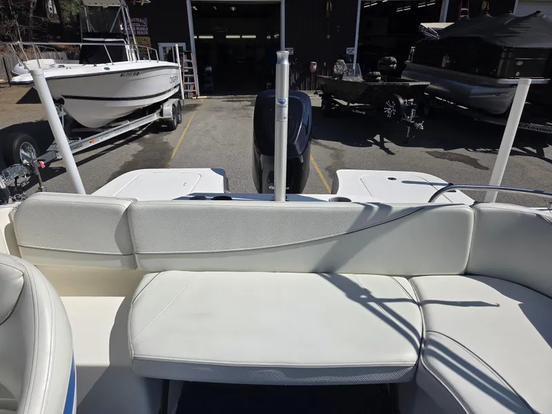 Slide: The Image of 2007 Bayliner 217 Deck Boat interior with white seating, parked in a marina. - 12
