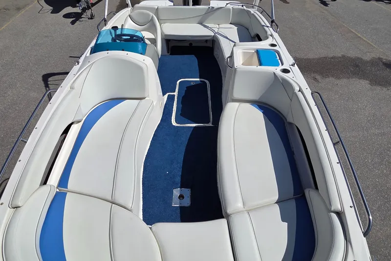 Slide: The Image of 2007 Bayliner 217 Deck Boat interior with white and blue seating, spacious layout. - 14