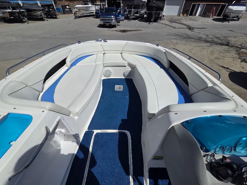 Slide: The Image of 2007 Bayliner 217 Deck Boat with spacious seating and blue accents, docked outdoors. - 20