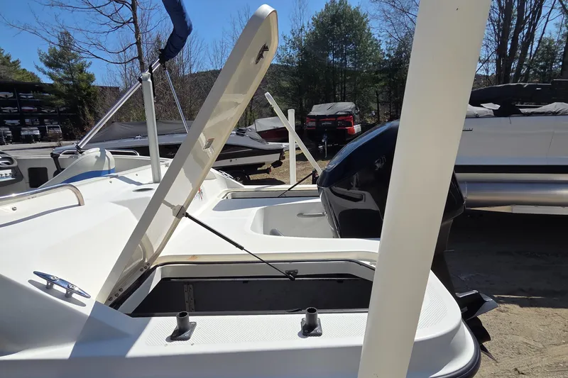 Slide: The Image of 2007 Bayliner 217 Deck Boat with open storage compartment, parked outdoors. - 6