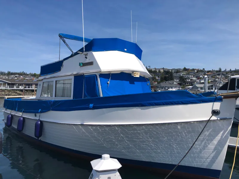 Slide: The Image of 1976 Grand Banks 42 Classic yacht with blue canopy docked in a marina. - 2
