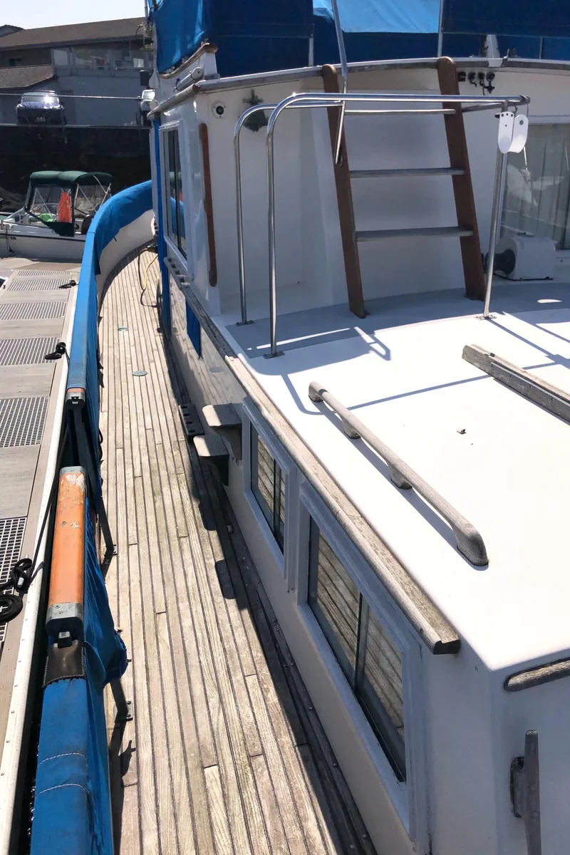 Slide: The Image of 1976 Grand Banks 42 Classic yacht with wooden deck and blue canopy, docked at marina. - 20