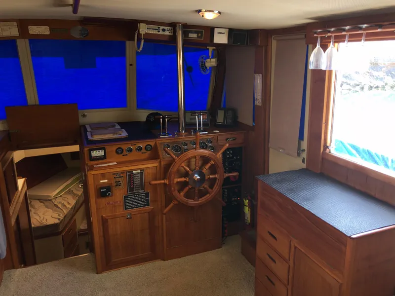 Slide: The Image of 1976 Grand Banks 42 Classic yacht interior with wooden helm, blue windows, and cozy cabin space. - 34