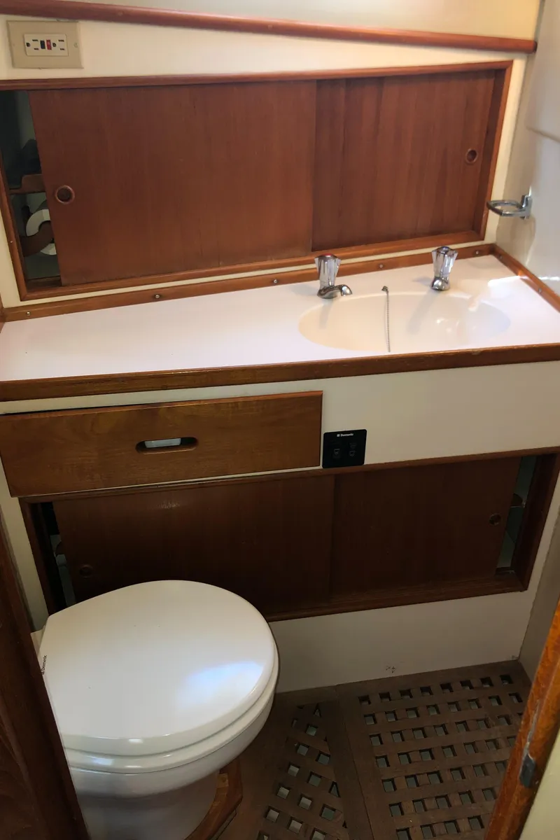 Slide: The Image of 1976 Grand Banks 42 Classic yacht bathroom with wooden cabinetry and white fixtures. - 48