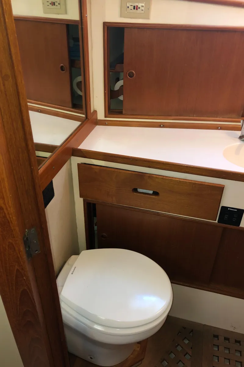 Slide: The Image of 1976 Grand Banks 42 Classic yacht bathroom with wooden cabinetry and white toilet. - 49