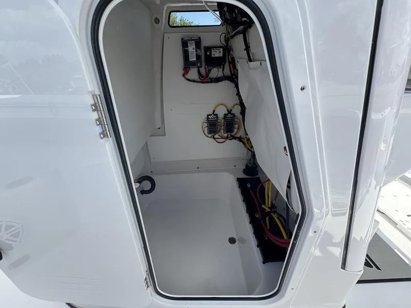 Slide: The Image of 2025 Sportsman Open 212 boat interior wiring compartment with open door. - 14