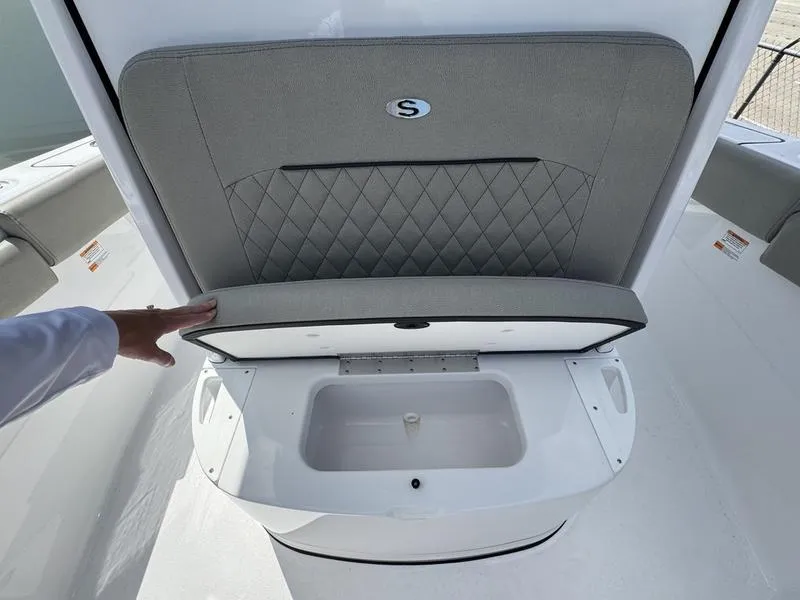 Slide: The Image of 2025 Sportsman Open 212 boat seat storage compartment with gray cushion and hand opening lid. - 18