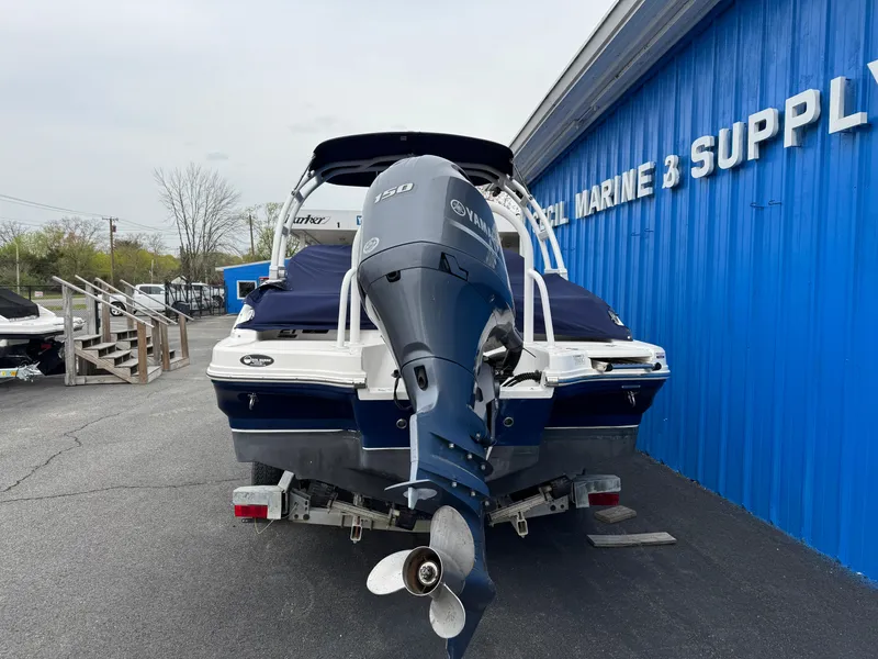 Slide: The Image of 2019 Chaparral 21 H2O Sport OB boat with outboard motor, parked near a blue building. - 3