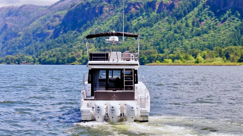 Slide: The Image of 2025 Jeanneau NC 1295 Fly cruising on a scenic lake with lush green hills. - 4