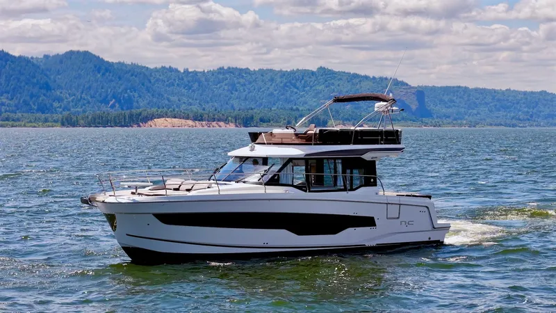 The Image of 2025 Jeanneau NC 1295 Fly yacht cruising on a scenic lake with mountains. - 0