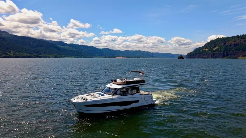 Slide: The Image of 2025 Jeanneau NC 1295 Fly cruising on a scenic lake under a clear blue sky. - 3