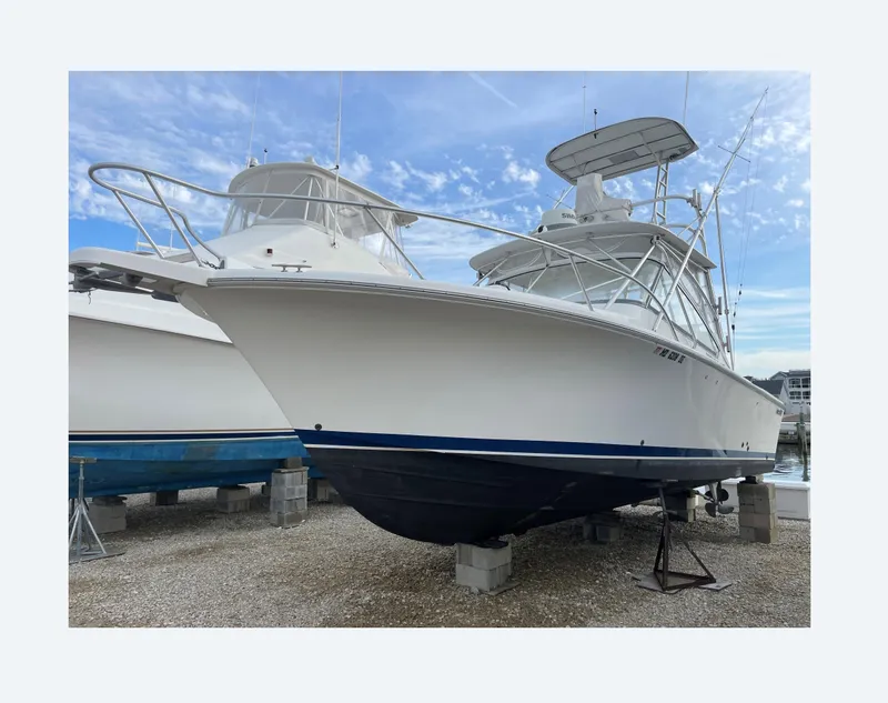 Slide: The Image of 2007 Luhrs 28 Open boat on dry dock, white hull, blue stripe, clear sky background. - 1