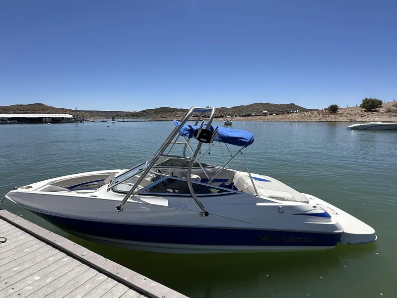 Slide: The Image of 2006 Larson 186 SENZA boat with blue accents docked on a sunny lake. - 13