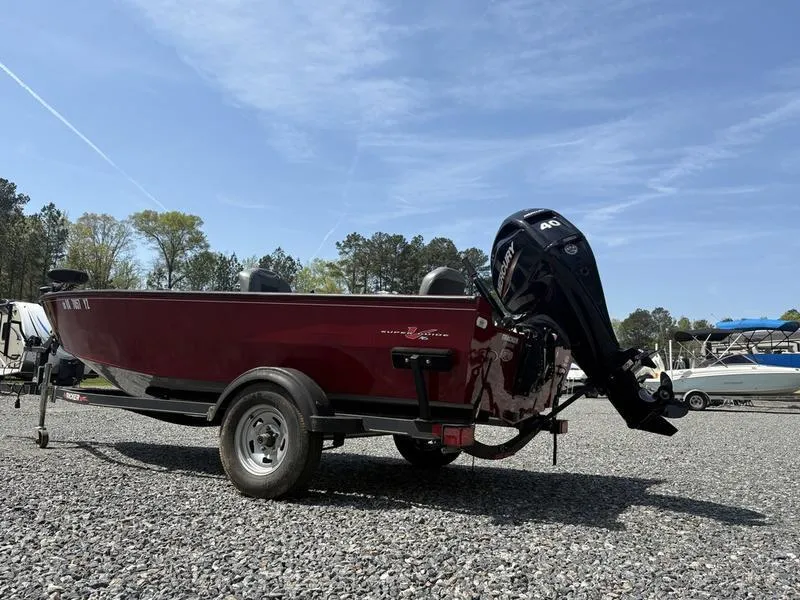 Slide: The Image of 2021 Tracker Super Guide V-16 T boat on gravel lot, featuring a powerful outboard motor. - 3
