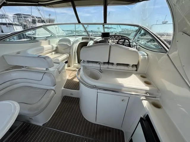 Slide: The Image of 2001 Maxum 3500 SCR yacht interior with white seating and helm, docked at marina. - 2