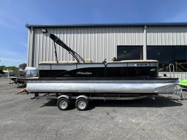 Slide: The Image of 2021 Manitou 23 Aurora LE VP pontoon boat on trailer, parked outside a building. - 1