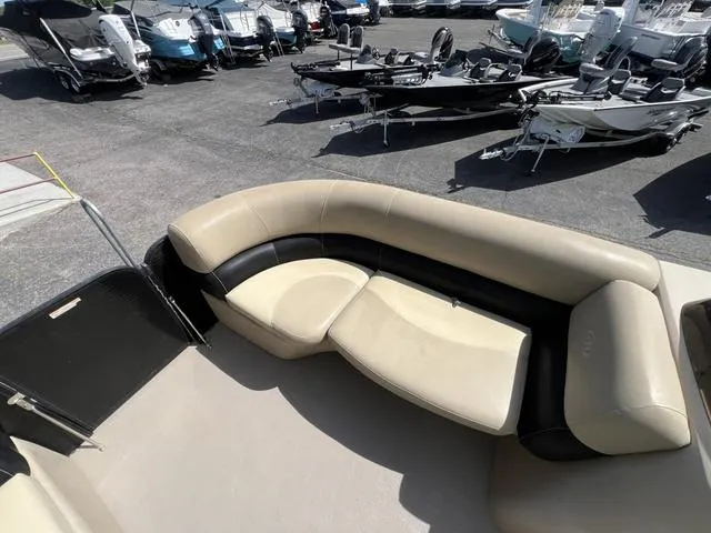 Slide: The Image of 2021 Manitou 23 Aurora LE VP boat interior with beige seating, surrounded by other boats. - 10