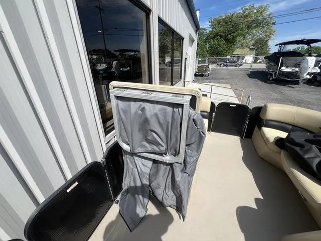 Slide: The Image of 2021 Manitou 23 Aurora LE VP pontoon boat interior with seating and cover, parked outdoors. - 12