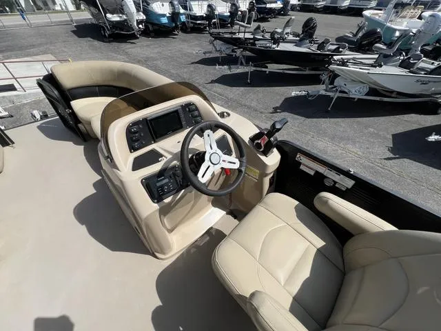 Slide: The Image of 2021 Manitou 23 Aurora LE VP boat interior with beige seating and modern dashboard. - 9