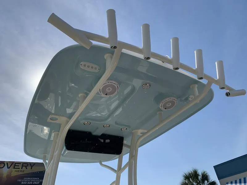 Slide: The Image of 2025 Pioneer ISLANDER 202 boat top with rod holders and speakers under clear sky. - 15