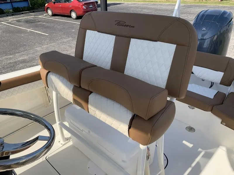 Slide: The Image of 2025 Pioneer ISLANDER 202 boat seating with brown and white upholstery in a parking lot. - 17