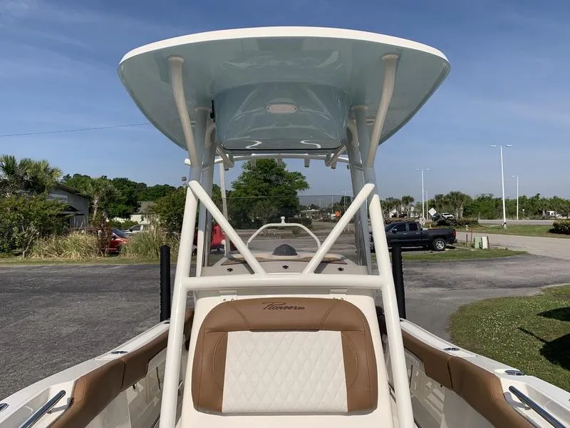 Slide: The Image of 2025 Pioneer ISLANDER 202 boat with T-top and cushioned seating, parked outdoors. - 31