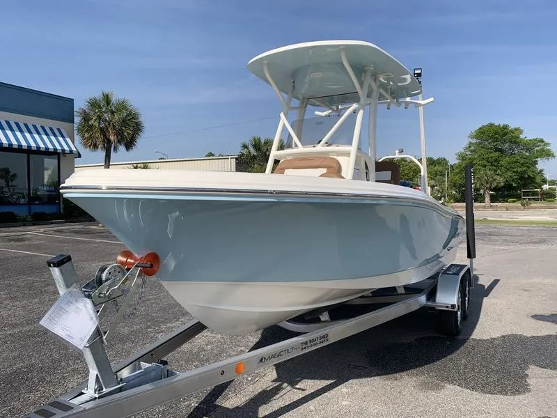 Slide: The Image of 2025 Pioneer ISLANDER 202 boat on trailer, parked outdoors under clear blue sky. - 8