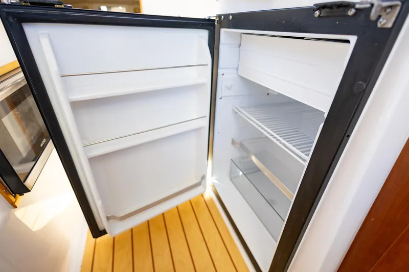 Slide: The Image of Open refrigerator inside 2019 Cutwater C-24 Coupe boat, showcasing interior shelves and freezer compartment. - 12