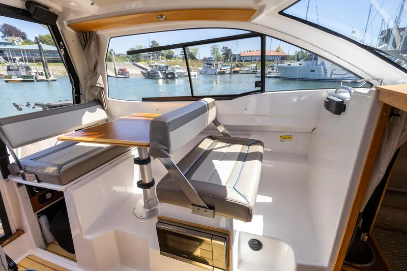 Slide: The Image of 2019 Cutwater C-24 Coupe interior with seating and table, overlooking marina. - 4