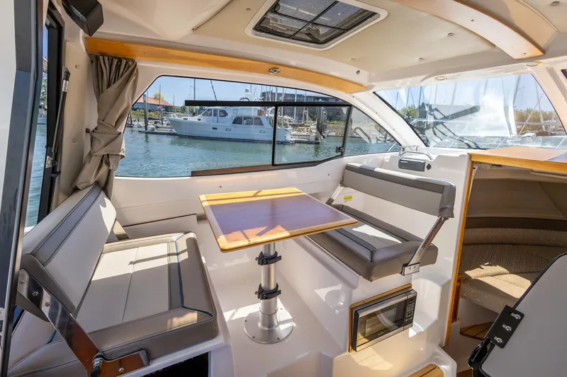 Slide: The Image of 2019 Cutwater C-24 Coupe interior with seating and table, marina view through windows. - 5